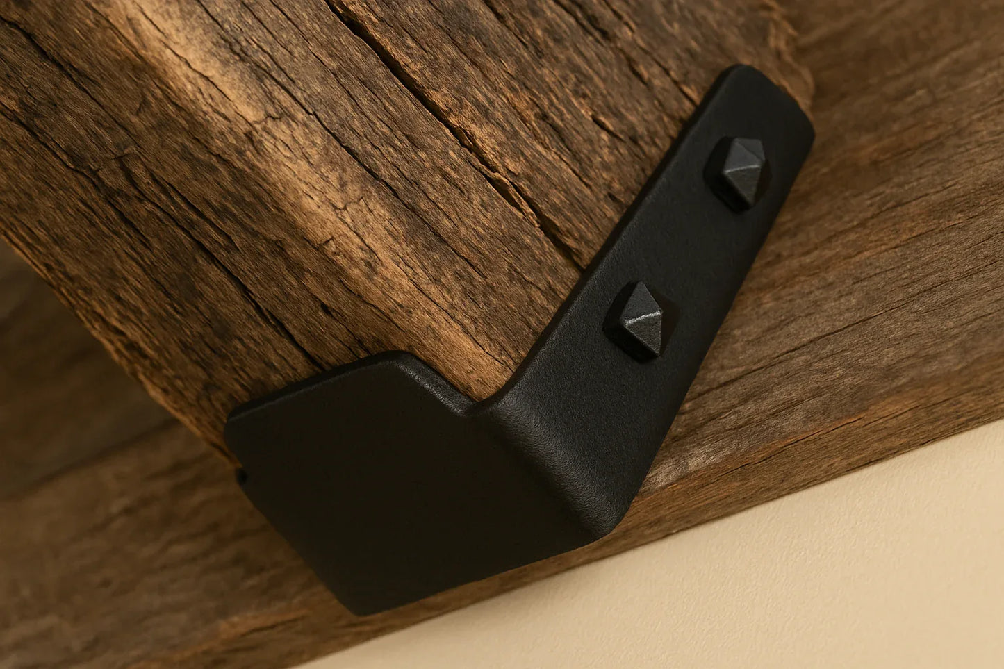 hand forged Black metal bracket with square screw heads on a wooden beam